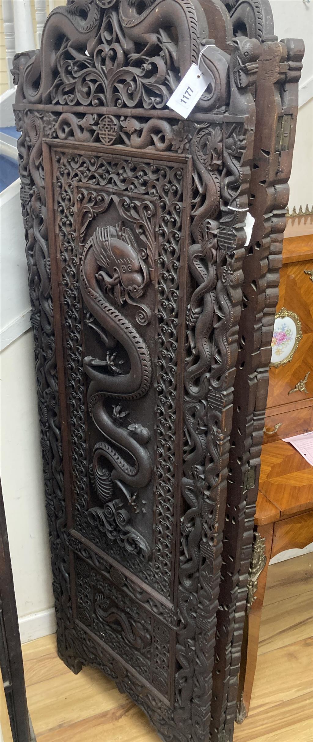 An early 20th century Burmese carved hardwood three fold dressing screen, each panel width 58cm, height 182cm